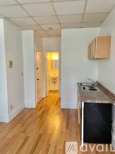 A kitchen with a black fridge and wooden floors.