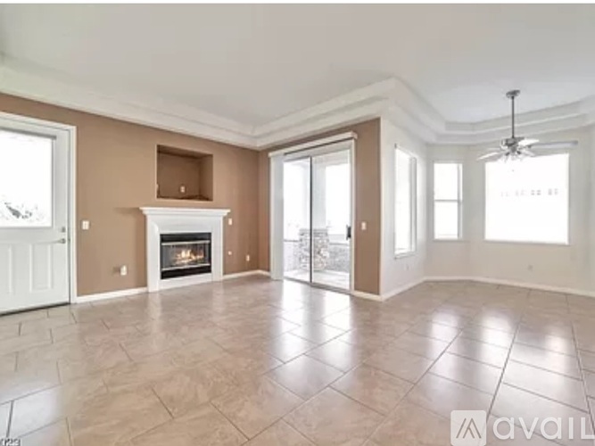 A spacious living room with a fireplace and a fan.