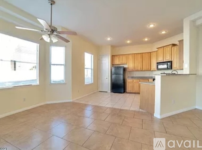 A spacious kitchen with wooden cabinets and a black refrigerator.