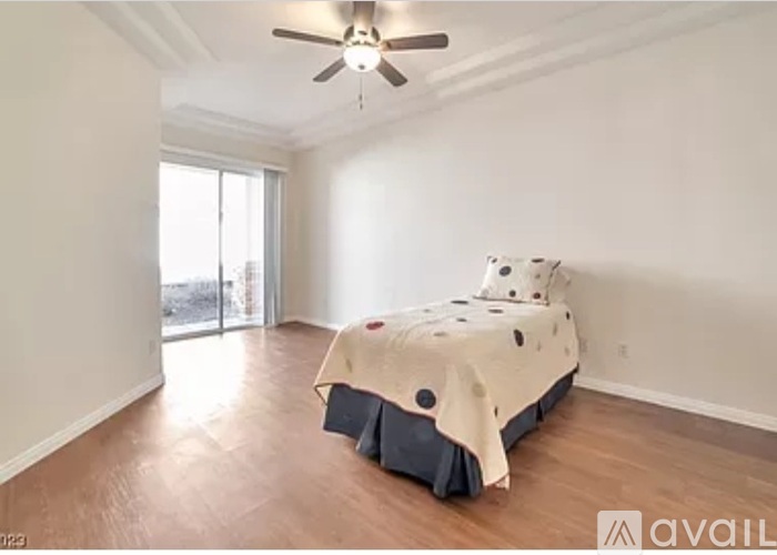 A bedroom with a bed covered in a blanket with a fan on the ceiling.