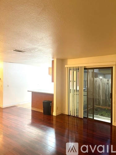 A room with wooden floors and a glass door leading outside.