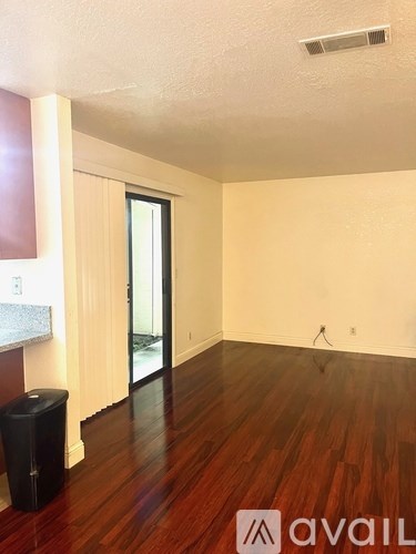 A room with wooden floors and a black trash bin.