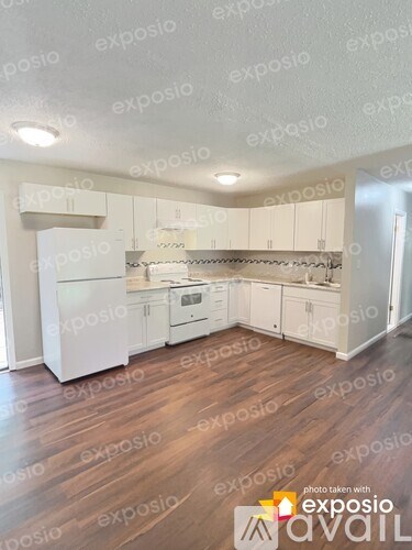 A kitchen with white appliances and wooden floors.
