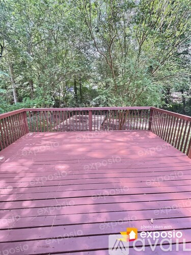 A wooden deck with a railing and trees in the background.