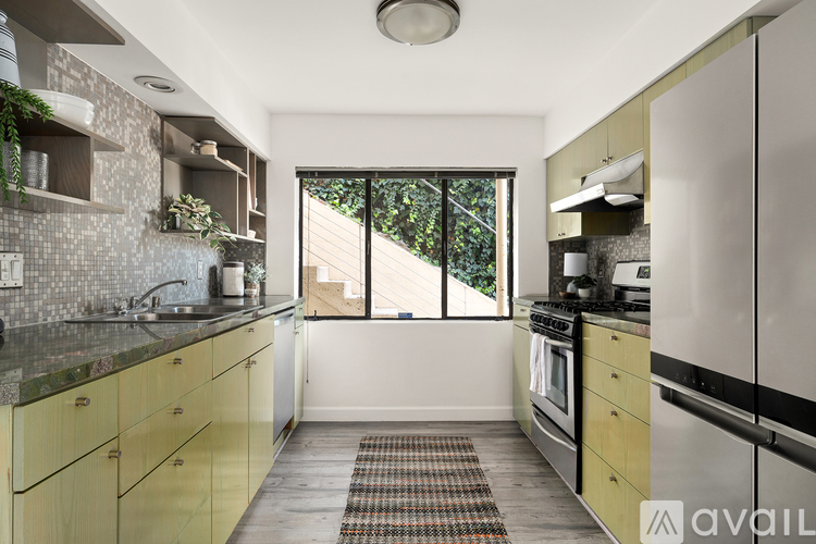 A kitchen with yellow cabinets and a black fridge.