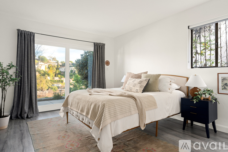 A bedroom with a large bed and a window with curtains.
