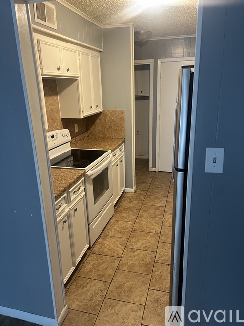 A kitchen with white cabinets and a refrigerator.