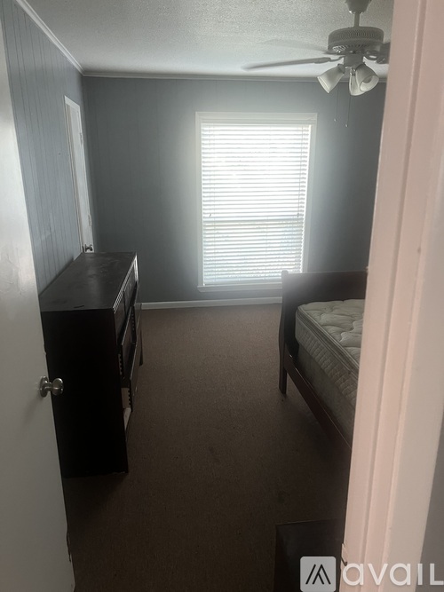 A bedroom with a bed, dresser, and window with blinds.