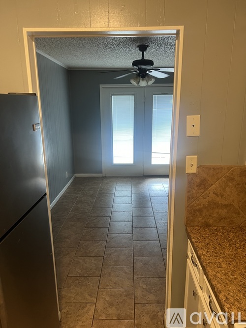 A kitchen with a refrigerator and a ceiling fan.