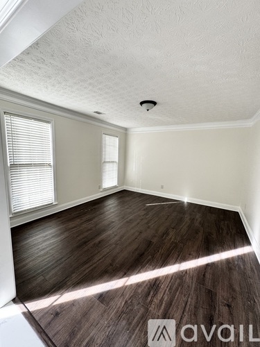 A room with wooden flooring and white walls.