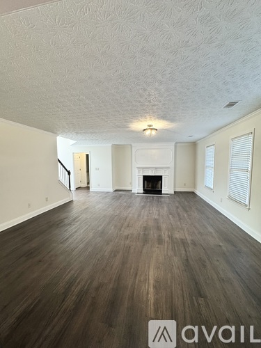 A spacious room with wooden flooring and a fireplace.