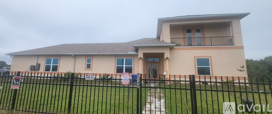 A two-story house with a black fence in front.