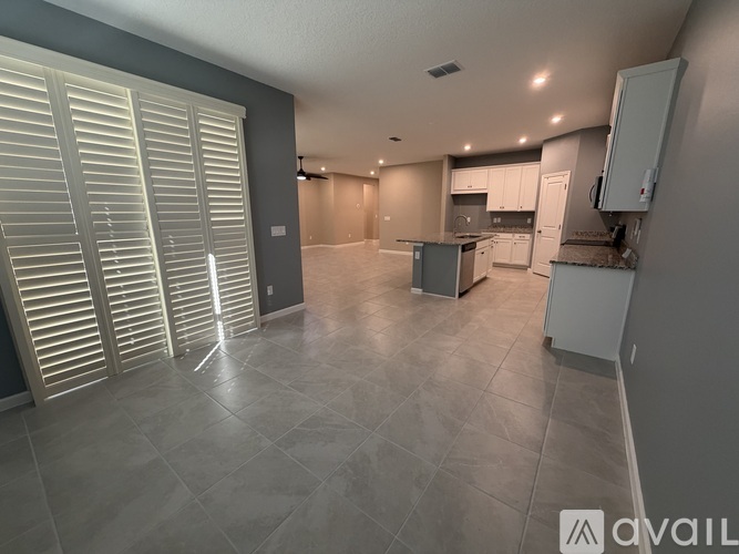 A spacious kitchen with white cabinets and a tiled floor.