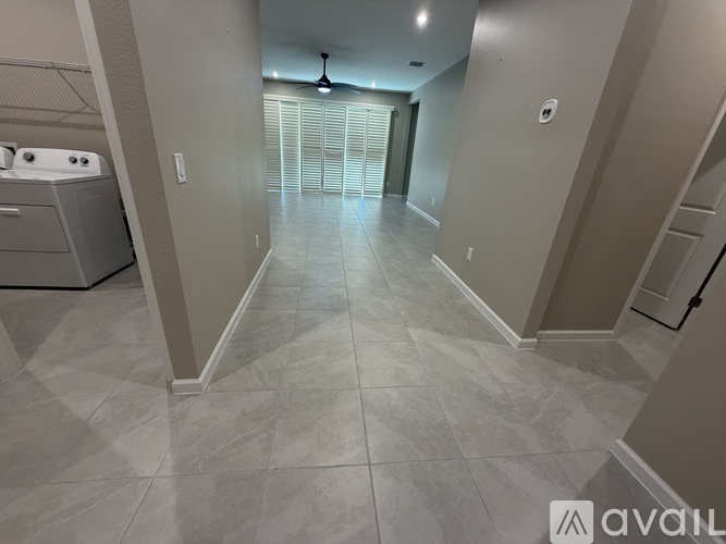A spacious hallway with tiled flooring and a washer and dryer in the corner.