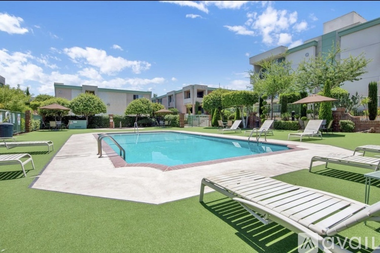 A pool surrounded by a white fence and a green lawn.