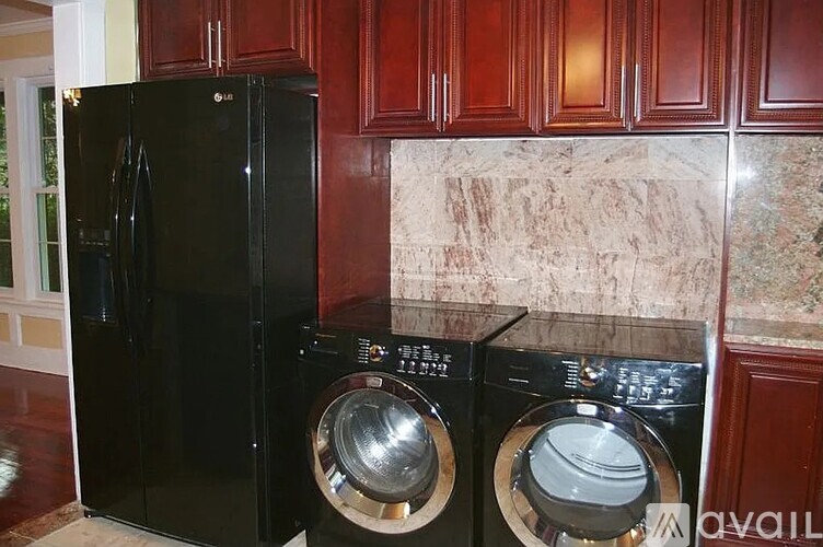 A black fridge and washer in a kitchen.