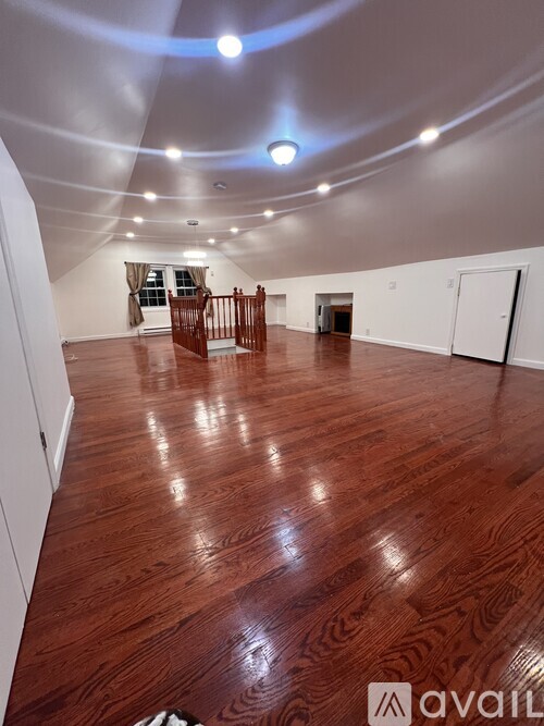 A spacious room with wooden flooring and a curved ceiling.