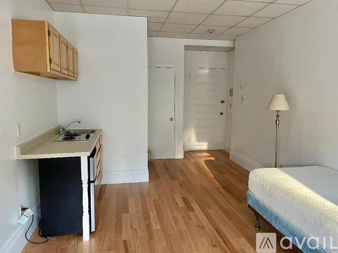 A room with a bed, a desk, and a cabinet.