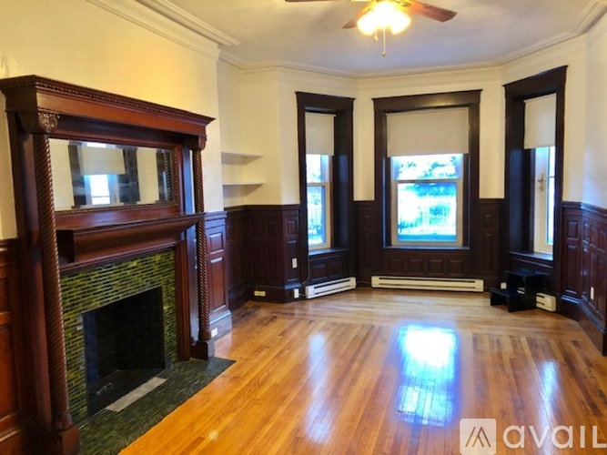 A large, empty room with wood floors and a fireplace.