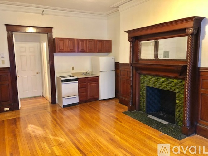 A living room with a fireplace and a kitchen in the background.
