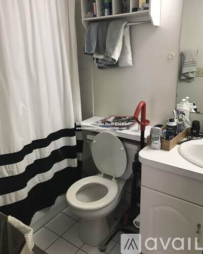 A white toilet in a bathroom with a black and white striped shower curtain.