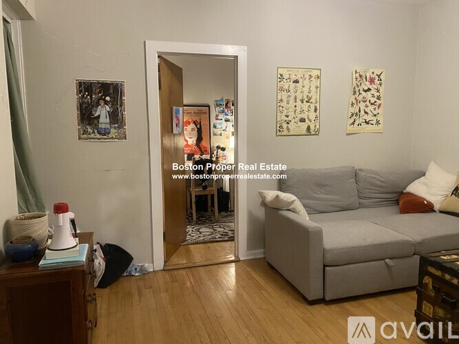 A living room with a grey couch and a wooden table with a vase on it.
