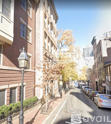 A street view of a residential area with parked cars and apartment buildings.