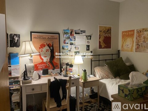 A room with a bed, desk, and a poster of a book cover.