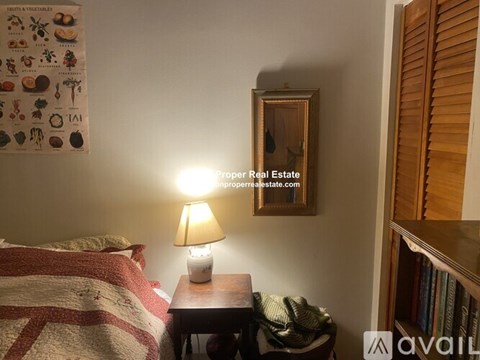 A bedroom with a bed, a lamp, and a picture frame on the wall.