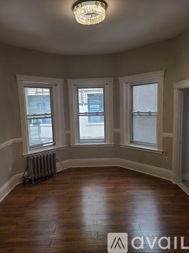 A room with wooden floors and three windows.