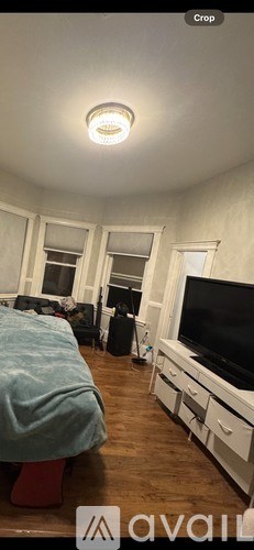 A bedroom with a bed, a dresser, and a television.