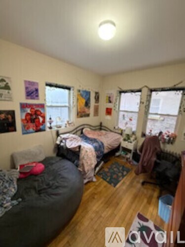 A bedroom with a bed, a chair, and a window.