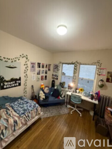 A bedroom with a bed, desk, and window.