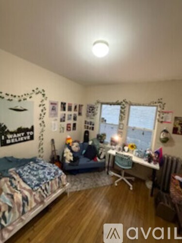A bedroom with a bed, desk, and window.