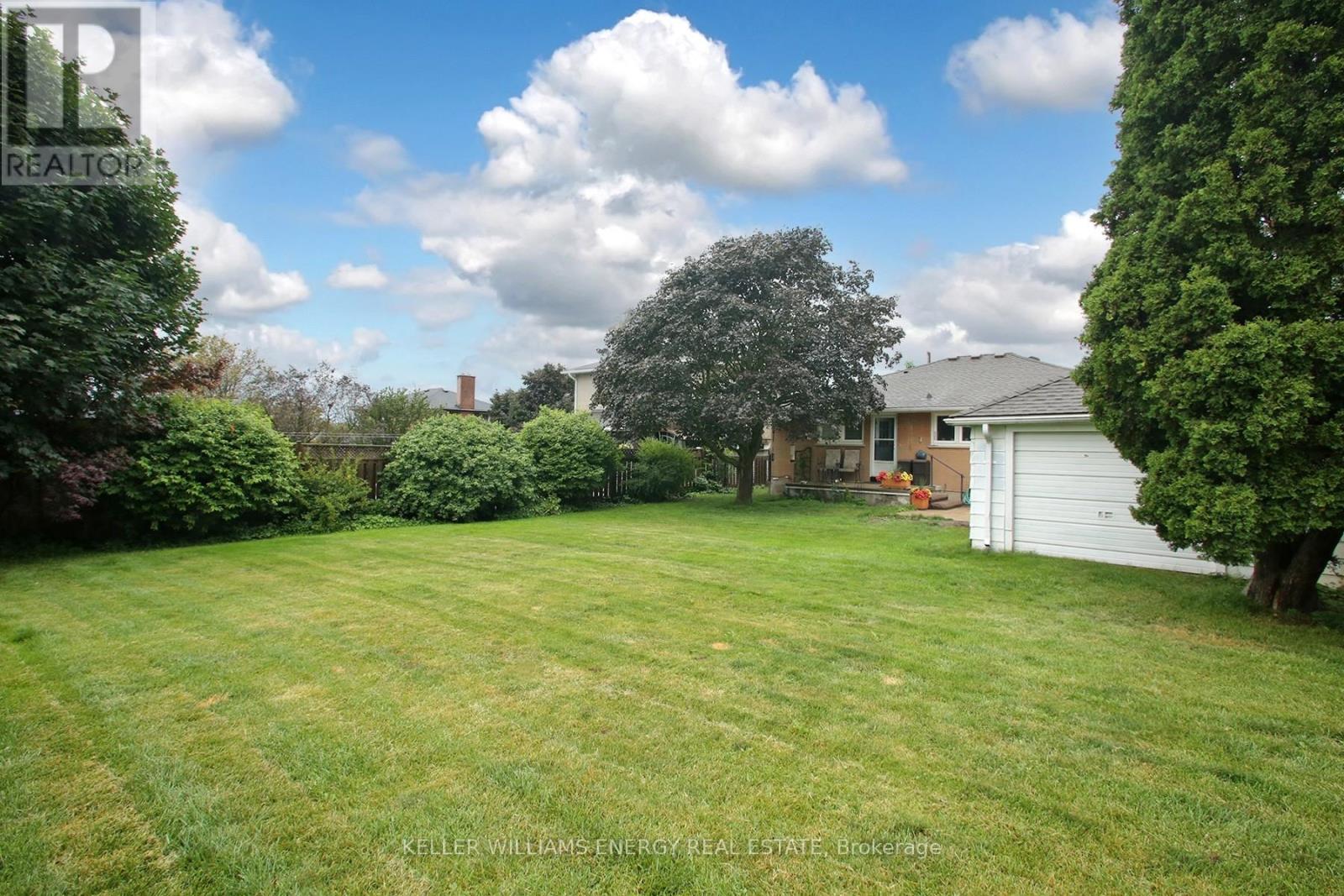 A backyard with a white fence and a house in the background.