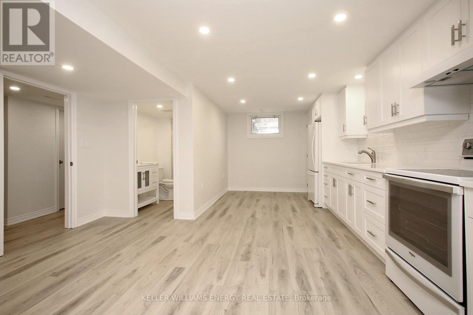 A spacious kitchen with white cabinets and a wooden floor.