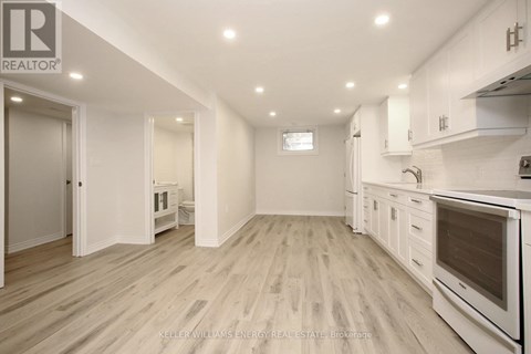 A spacious kitchen with white cabinets and a wooden floor.