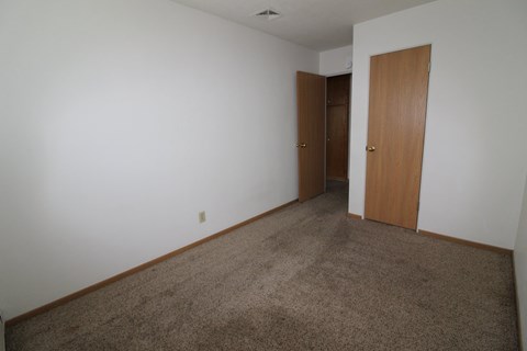 A room with carpeted floor and two doors.