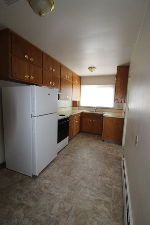 A kitchen with a white refrigerator and wooden cabinets.