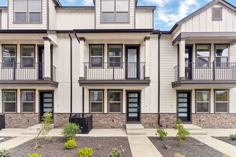 A row of modern townhouses with black railings and doors.