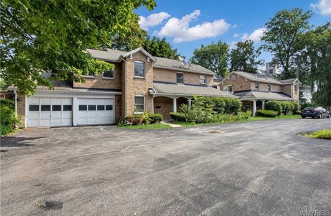 A large house with a garage is surrounded by trees.