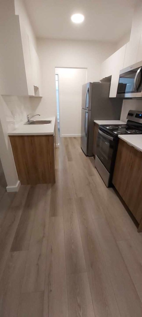 A kitchen with a refrigerator, microwave, and oven.