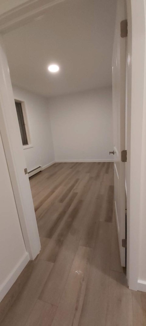 A room with wooden flooring and white walls.