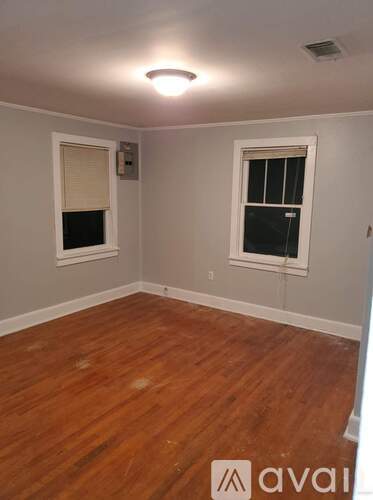 A room with wooden floors and two windows.