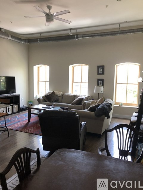A living room with a couch, chairs, and a ceiling fan.
