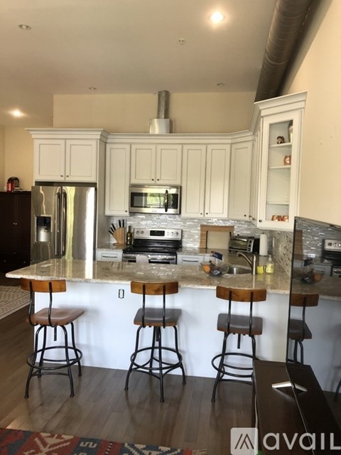 A kitchen with a marble countertop and bar stools.