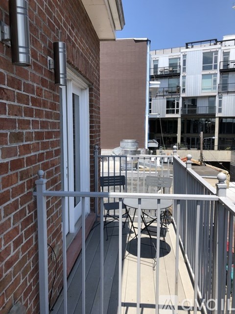 A balcony with a table and chairs overlooking a building.