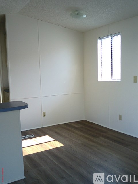 A room with a window and a wooden floor.