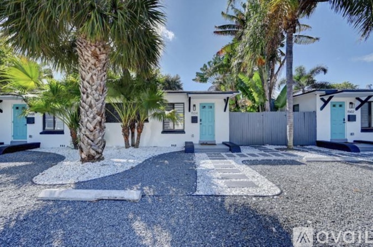 A row of houses with blue doors and a palm tree in the foreground.