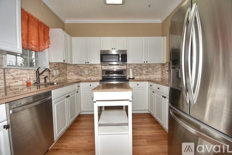 A kitchen with white cabinets and a stainless steel refrigerator.